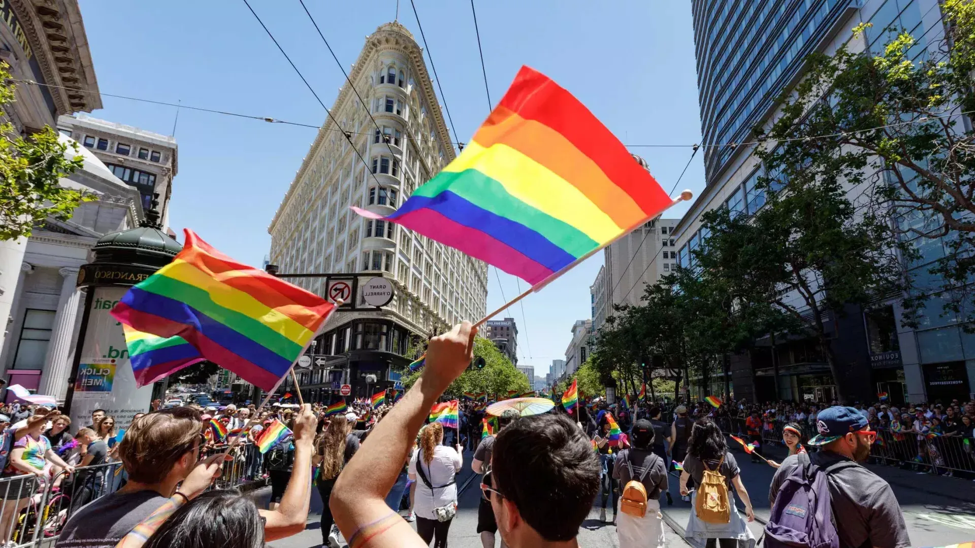 Menschen, die an der San Francisco Pride Parade teilnehmen, schwenken Regenbogenfahnen.